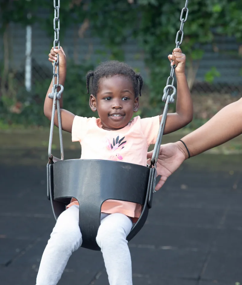 A little girl smiling on a swing.